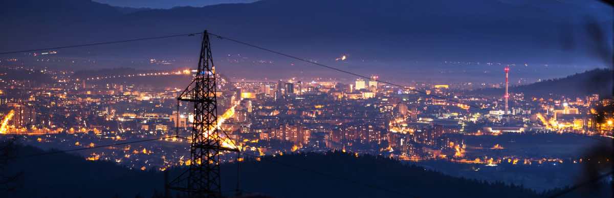 Power transmission lines to night city scape